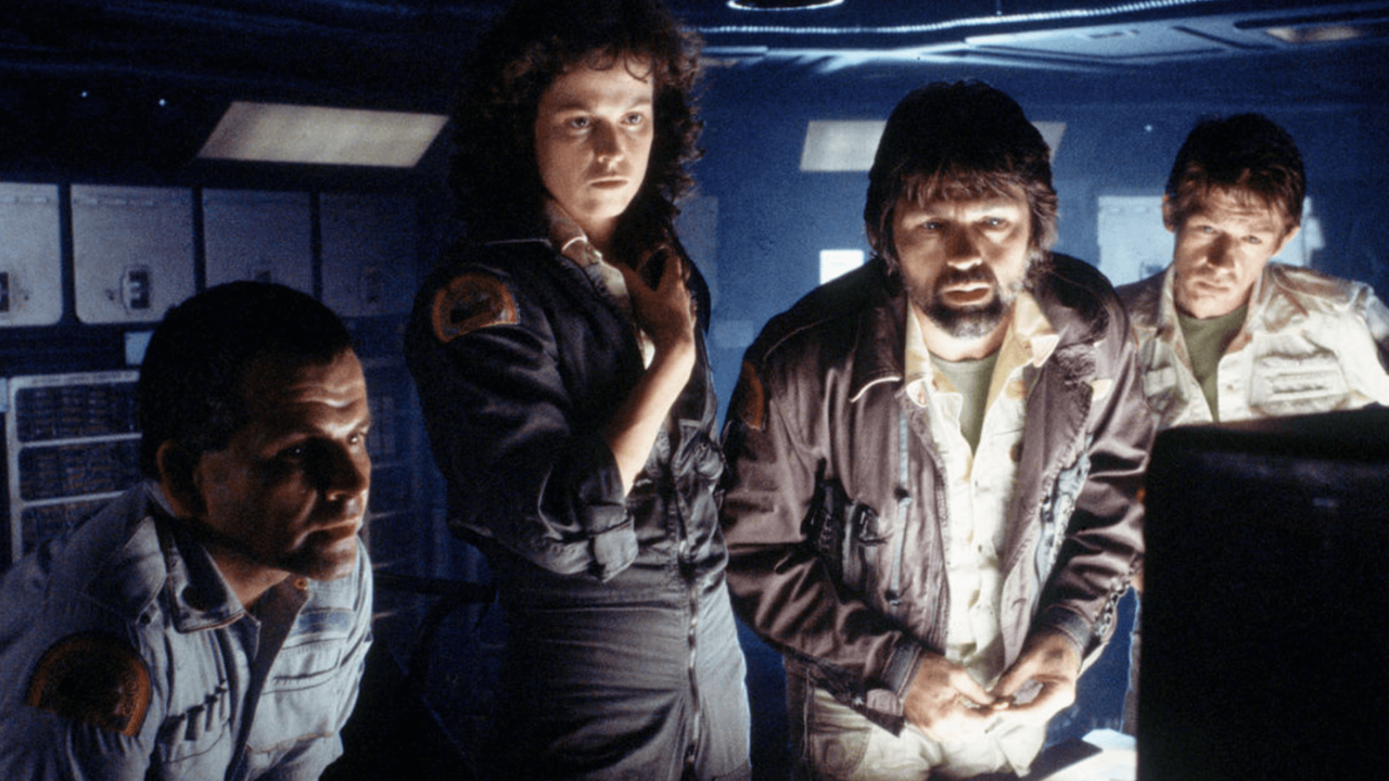 A tense scene from Alien (1979) showing four Nostromo crew members intently watching a monitor in a dimly lit ship interior, faces lit by the screenâs eerie glow.