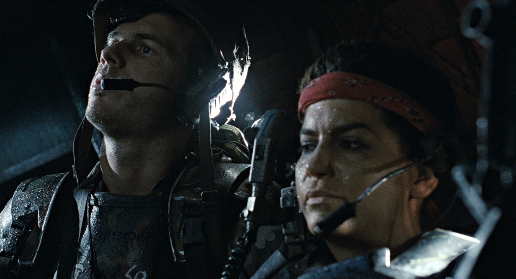 Close-up of Hudson and Vasquez in Aliens (1986), both wearing military gear and headsets, faces glistening with sweat as they scan the darkness for unseen threats.